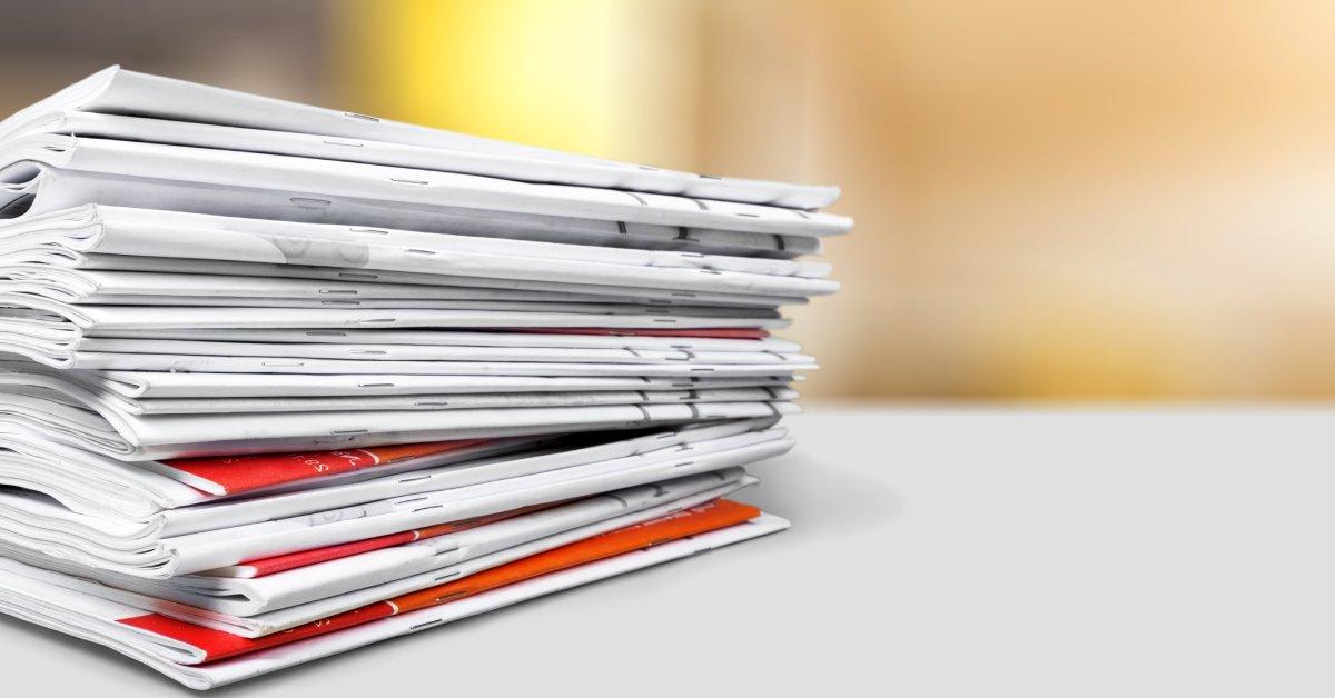 A close-up of a stack of stapled booklets, featuring red and orange design elements, placed on a white surface.