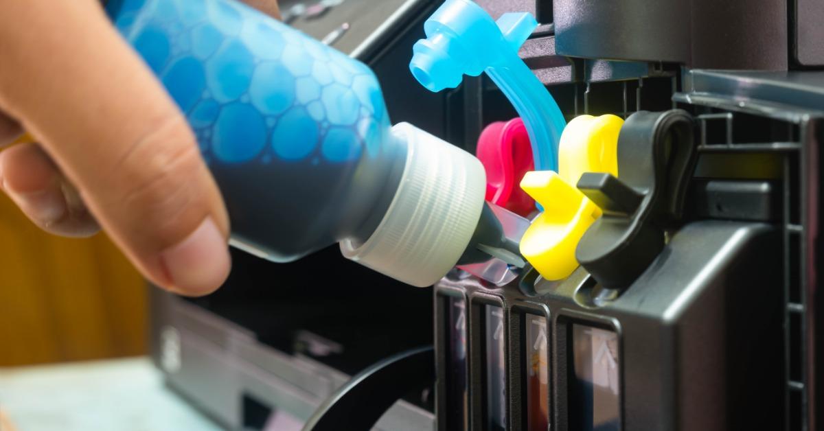 A close-up of several ink cartridges in a large printer with colored labels, plastic housings, and an internal area.